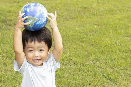 地球儀を持って草原で立っている男の子 男の子,地球,地球儀の写真素材
