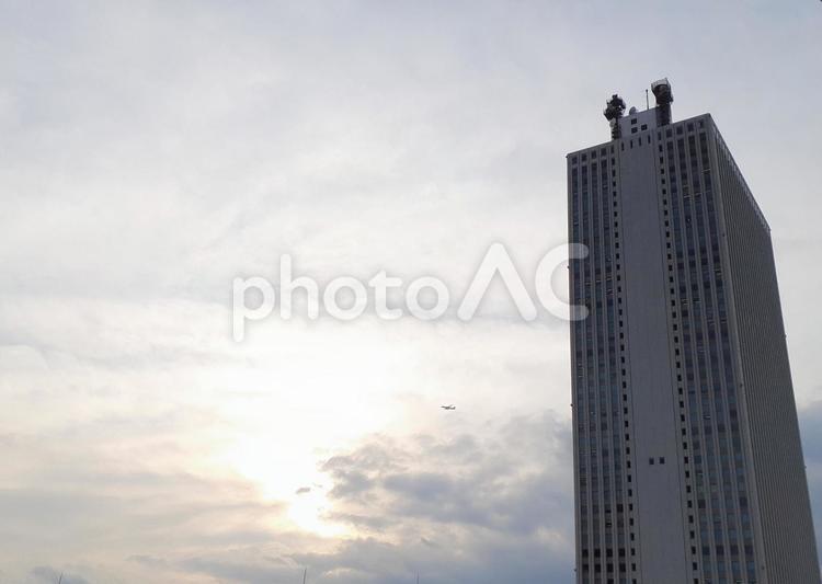 都会　高層ビル　陽の光を飛行機が飛ぶ 高層ビル,飛行機,飛行の写真素材