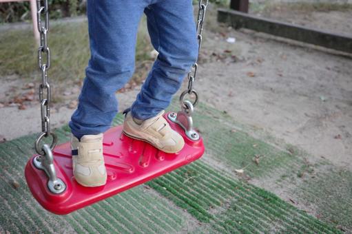 公園のブランコに乗る子どもの足元 ブランコ,子ども,公園の写真素材
