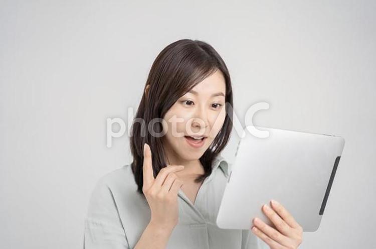 タブレットを持って驚く女性・白背景 女性,ビジネス,タブレットの写真素材