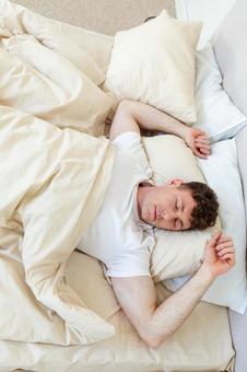 ベッドで両手を上げて寝る男性 縦,男性,外国人の写真素材