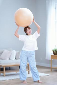 頭の上でバランスボールを持つ女性 女性,バランスボール,持つの写真素材