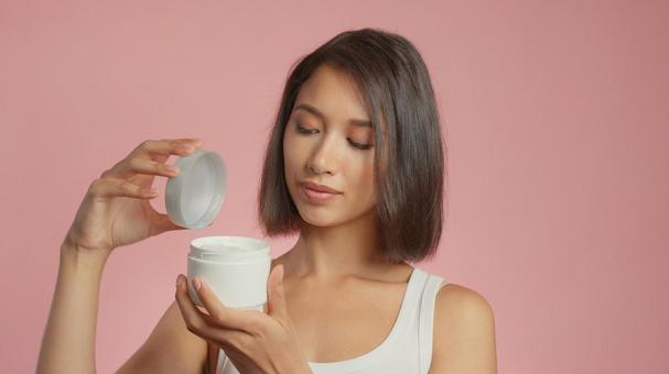 クリームジャーの蓋を開けた女性 クリームジャーの蓋を開けた女性の写真