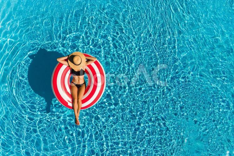 プールで浮き輪の上に座ってくつろぐ女性 女性,人物,プールの写真素材