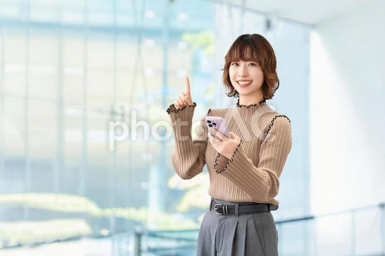 スマホを持って案内をする笑顔の女性 女性,スマホ,笑顔の写真素材