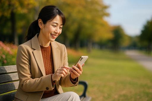 スマホを外で触る女性 スマホを外で触る女性の写真