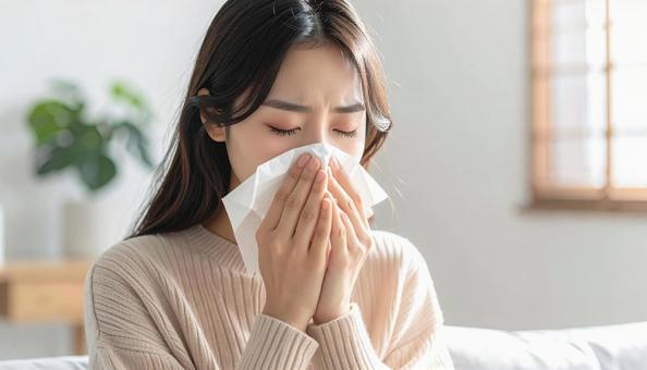 ティッシュで鼻をかむ日本人の若い女性の写真