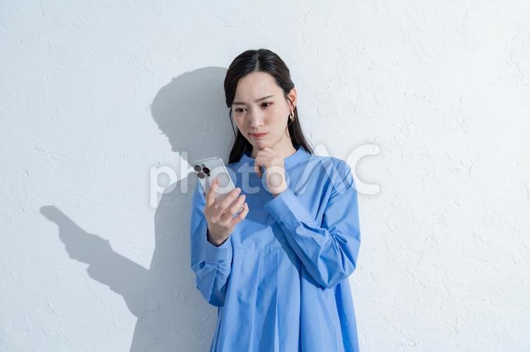 携帯を持つ青いワンピースを着た女性 スマートフォン,スマホ,女性の写真素材