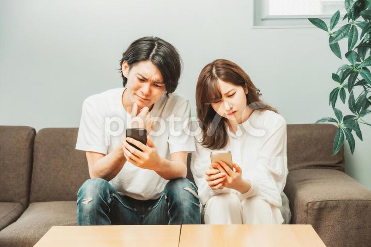 部屋でスマホを使う男女（困る） スマホ,トラブル,困るの写真素材