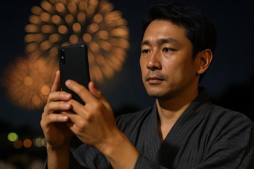 スマホで花火を撮る男性 スマホで花火を撮る男性の写真