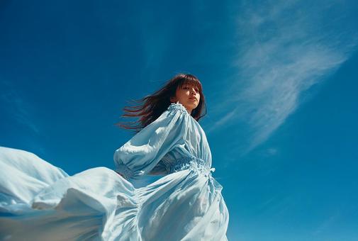 広がる空と軽やかなドレスを纏う女性 広がる空と軽やかなドレスを纏う女性の写真
