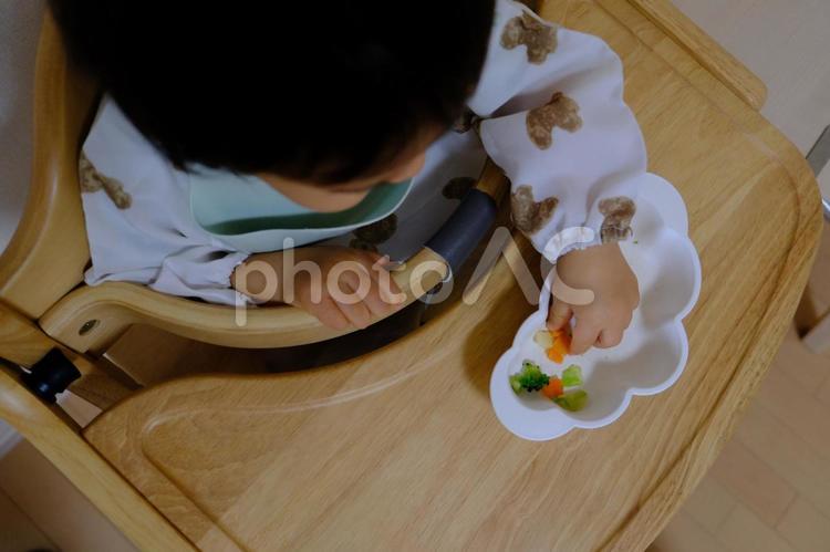 ハイチェアで野菜を手づかみ食べする子ども 手づかみ,離乳食,子どもの写真素材