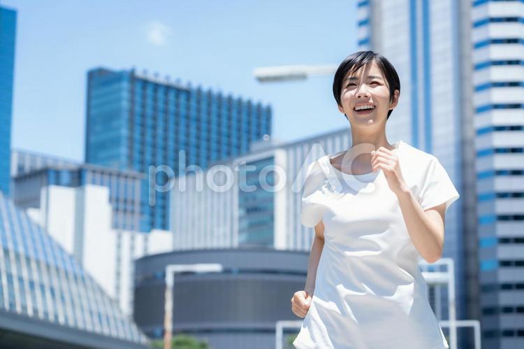 オフィス街をジョギングする若い女性 ランニング,ジョギング,フィットネスの写真素材