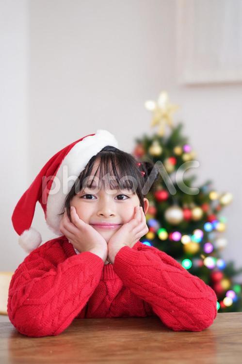 サンタ帽子を被り頬杖をする笑顔の女の子 女の子,サンタ帽子,頬杖の写真素材