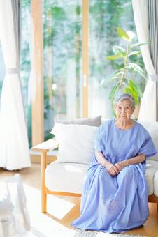 カメラ目線でソファに座る青い服の女性 女性,ソファ,座るの写真素材