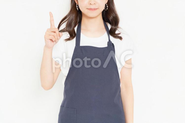 白い背景の前に立って、ポイントを示すエプロン姿の若い女の子 エプロン,若い,女の子の写真素材