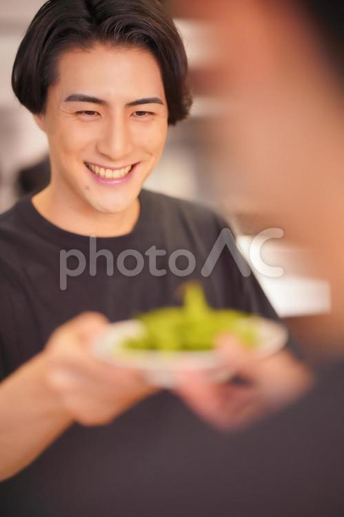 枝豆を渡す男性（縦） 男性,大学生,バイトの写真素材