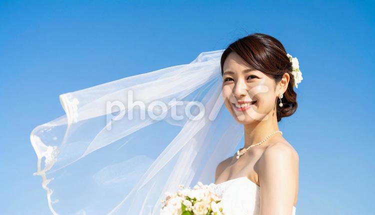 青空にベールがなびくウエディング姿の花嫁 花嫁,ウェディング,ウェディングドレスの写真素材
