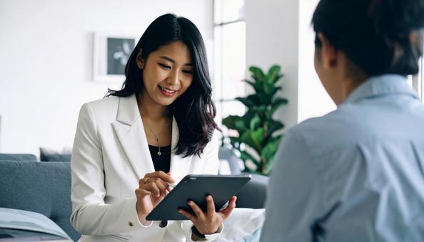 タブレットを使って説明する女性営業マンの写真