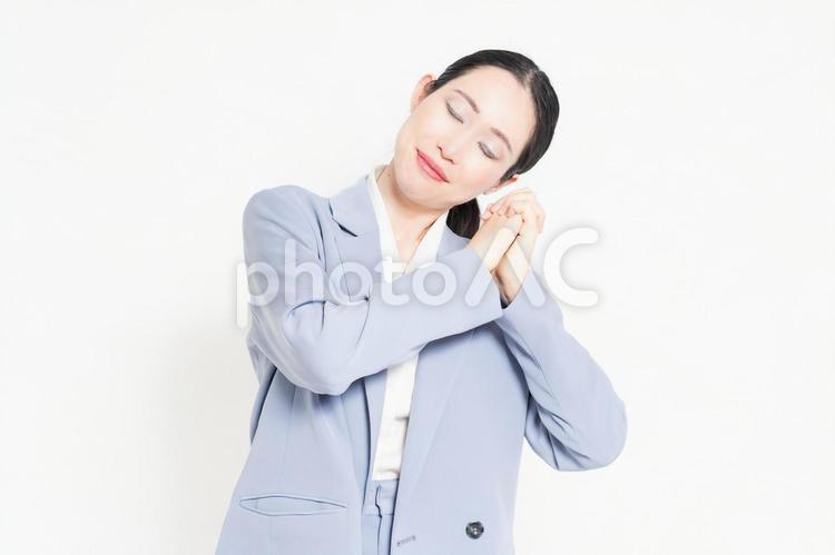 白バックの前に立って、お願いのジェスチャーをする女性 お願い,祈る,頼むの写真素材