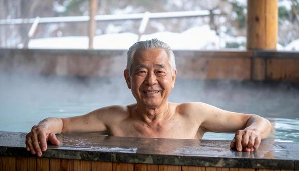 温泉につかってリラックスするシニア男性 温泉につかってリラックスするシニア男性の写真