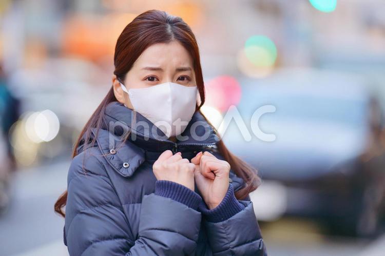 街にいるマスクをしたダウンコートの寒そうな女性 女性,日本人,1人の写真素材