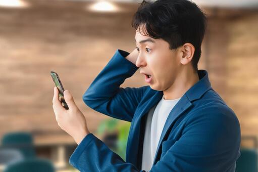 スマホを見て驚く男性ビジネスマン 男性,スマホ,スマートフォンの写真素材