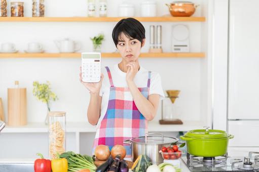 電卓を持って悩む主婦。 電卓を持って悩む主婦。の写真