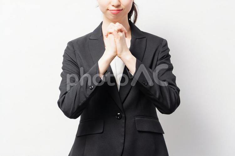 白バックの前に立って、お願いのジェスチャーをするビジネスウーマン 女性,お願い,祈るの写真素材
