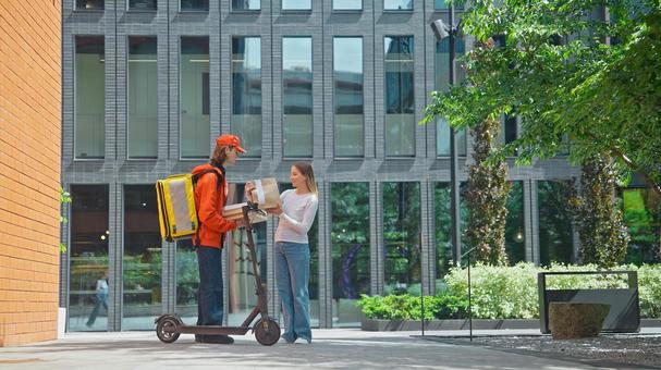 ビルの前でフードデリバリーを受け取っている女性 配達,フードデリバリー,デリバリーの写真素材