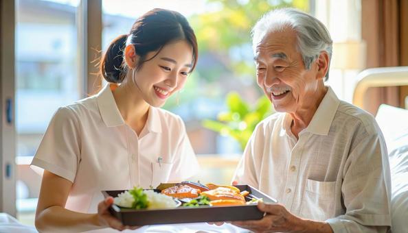 高齢男性と女性介護士の穏やかな食事風景の写真
