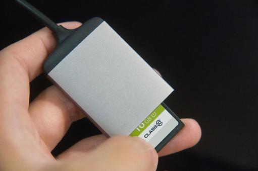 手に持ったSDカードリーダー 手に持ったSDカードリーダー sdカード,sdカードリーダー,メモリーカードの写真素材