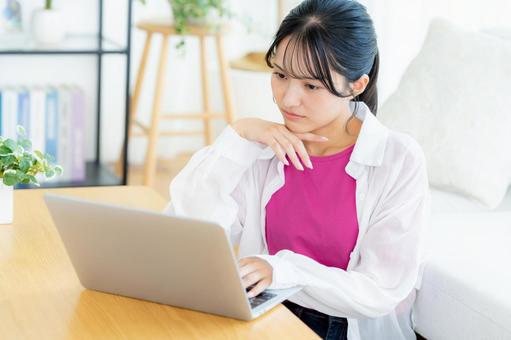 自宅でノートパソコンを操作する若い女性 若い女性,ノートパソコン,笑顔の写真素材