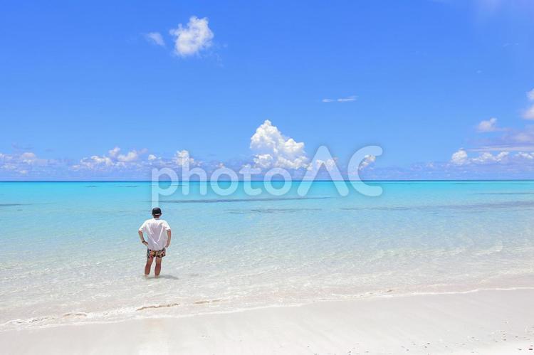 浅瀬の海に一人で立つ男性 砂浜,1人,ビーチの写真素材