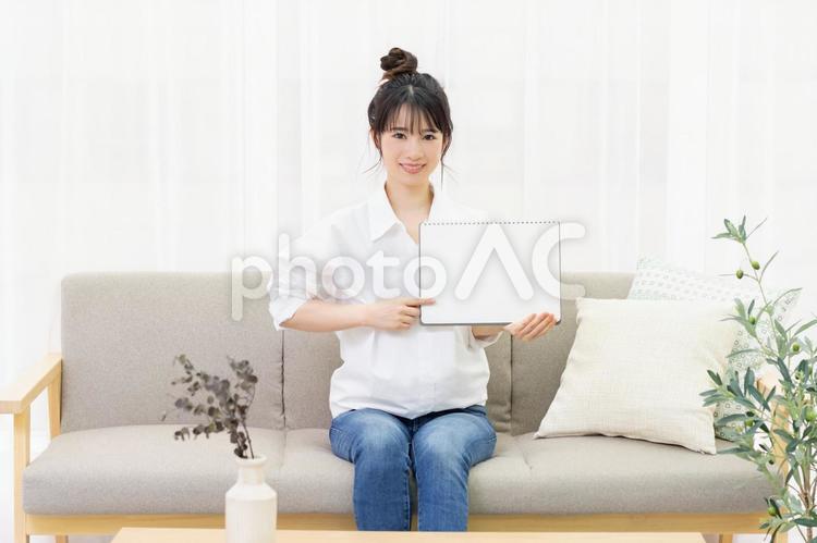 ソファに座って小さいスケッチブックを持つ若い女性 女性,ソファ,家の写真素材