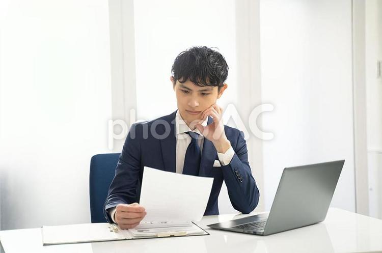 パソコンと書類チェックするビジネス男性 ビジネス,オフィス,デスクワークの写真素材