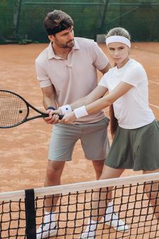 フォームを確認する男女のテニス練習の写真