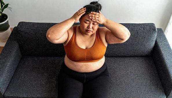 肥満で疲れやすく、額に手をやる女性 肥満で疲れやすく、額に手をやる女性の写真