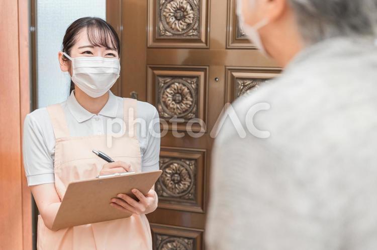 高齢者住宅に訪問する女性（書類・マスク） 民生委員,見守り,カウンセリングの写真素材