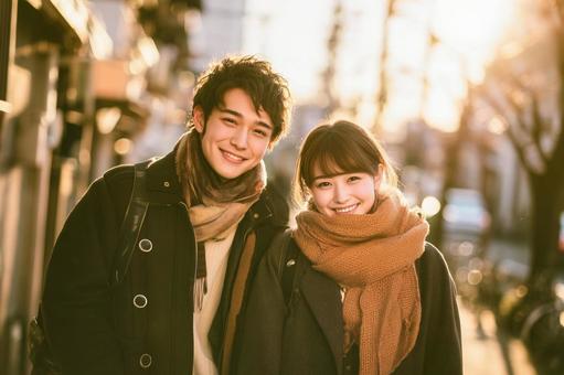 秋の夕暮れの街並みを背景に笑顔のカップル 秋の夕暮れの街並みを背景に笑顔のカップルの写真