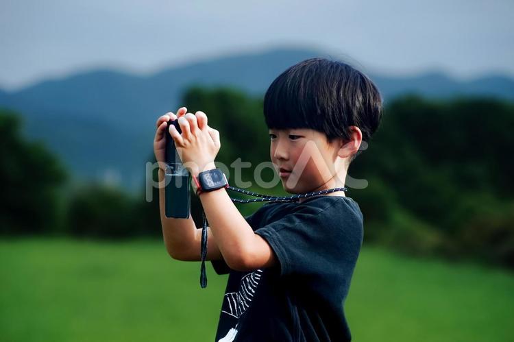 ＜人物＞スマホで写真を撮る夏休みの男の子 子供,男性,人物の写真素材