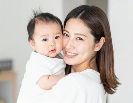 赤ちゃんを抱いて微笑んでいる若いお母さん 赤ちゃんを抱いて微笑んでいる若いお母さんの写真