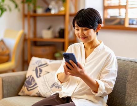 自宅でスマホを操作する女性の写真