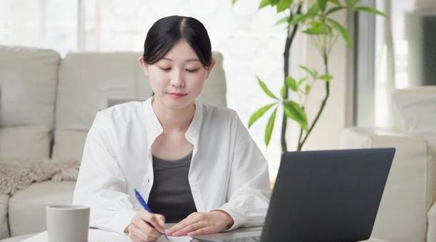 リビングで勉強をするアジア人女性 リビングで勉強をするアジア人女性の写真