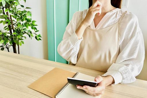 電卓で計算するエプロン姿の女性 電卓で計算するエプロン姿の女性 家計,節約,主婦の写真素材