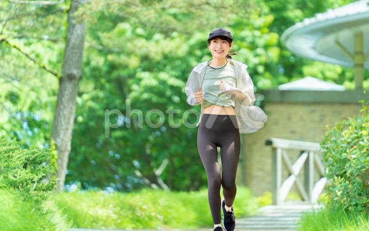 緑の中でジョギングをする女性 女性,運動,スポーツの写真素材