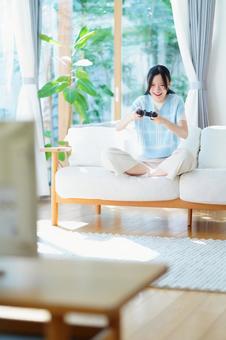 ソファに座りゲームに夢中の女性 女性,日本人,コントローラーの写真素材