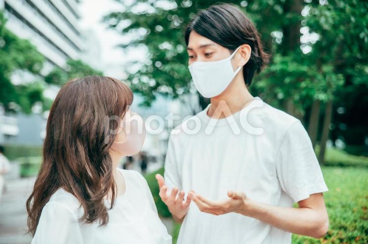 マスクをして何かを話す若いカップル マスク,飛沫,コロナの写真素材