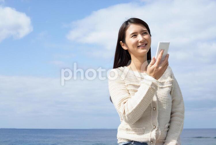 海岸で寛ぐ女性 女性,携帯電話,スマートフォンの写真素材