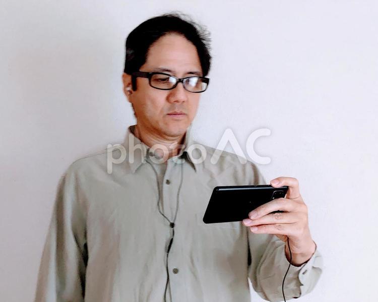 イヤホンで動画視聴している男性 イヤホン,イヤフォン,仕事の写真素材